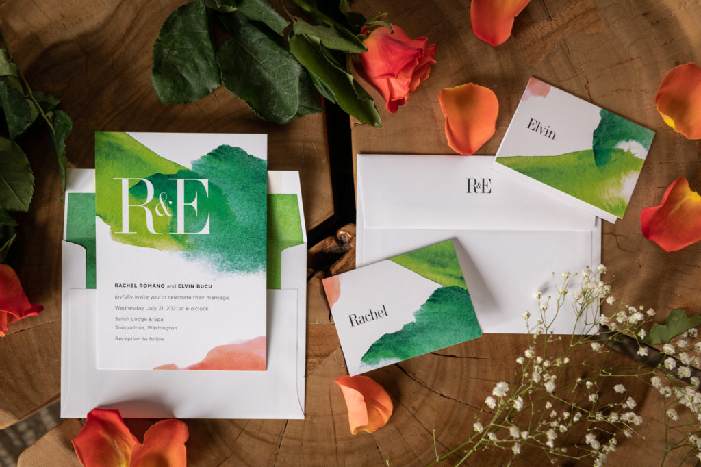 Flat-lay of wedding invitation and escort cards on wooden table with rose petals