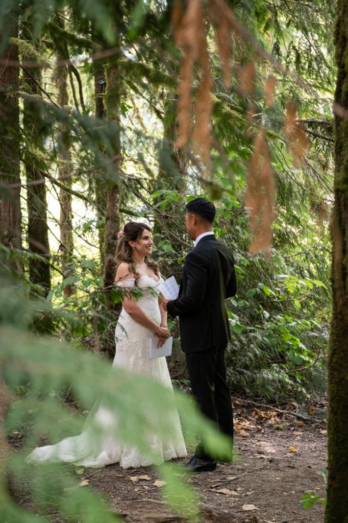 Bride and groom sharing vows in alcove surrounded by tall trees