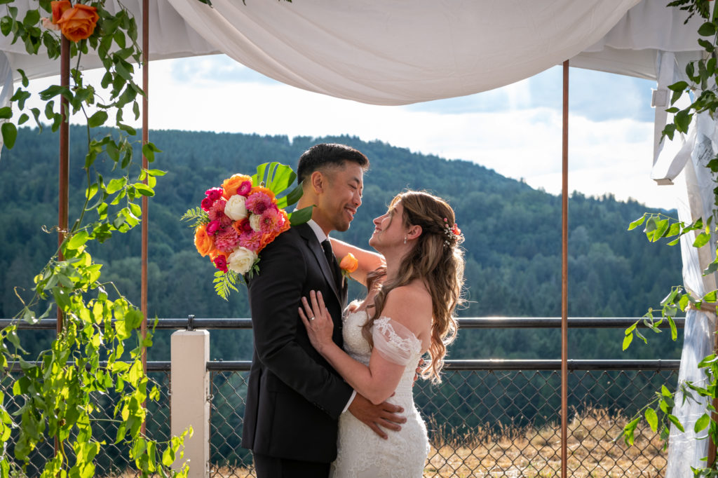 Bride and groom embracing under floral altar setup at Salish Lodge & Spa