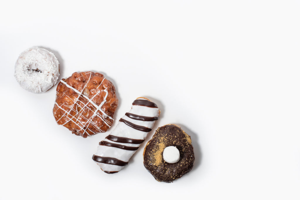 Flat-lay photo of four doughnuts on white backdrop