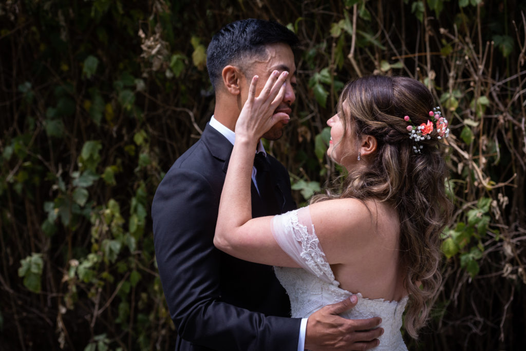 Bride wiping tear from groom's eye as they embrace