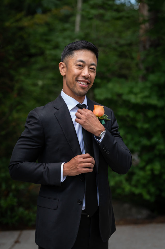 Portrait of groom smiling and adjusting his tie