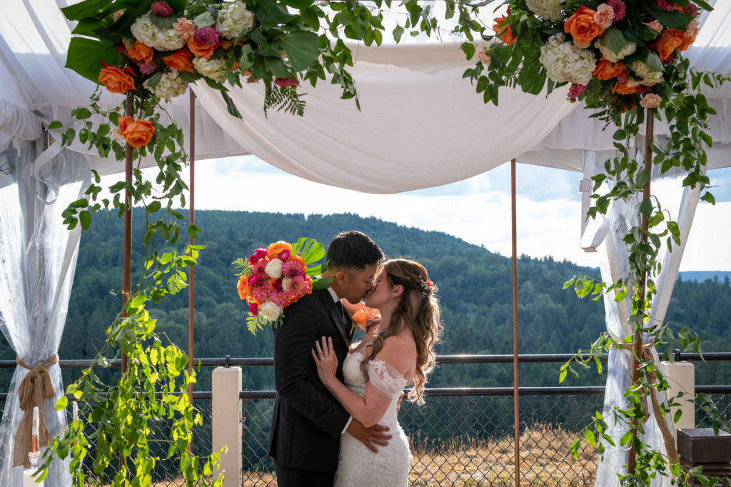 Bride and groom kissing under floral altar setup at Salish Lodge & Spa