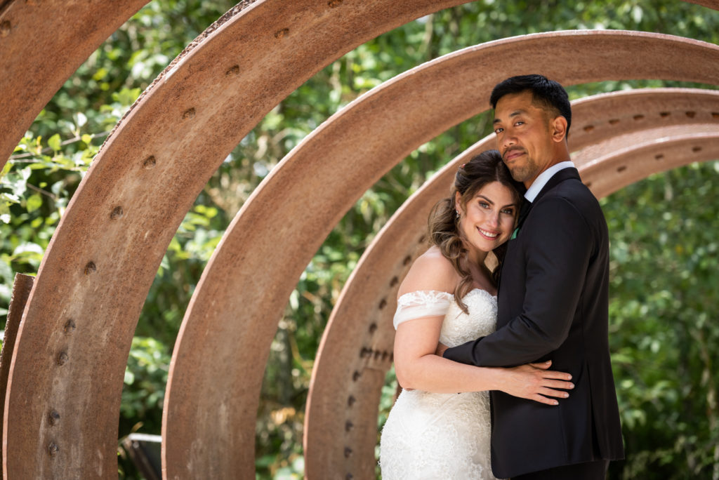 Bride and groom embracing within metal tunnel