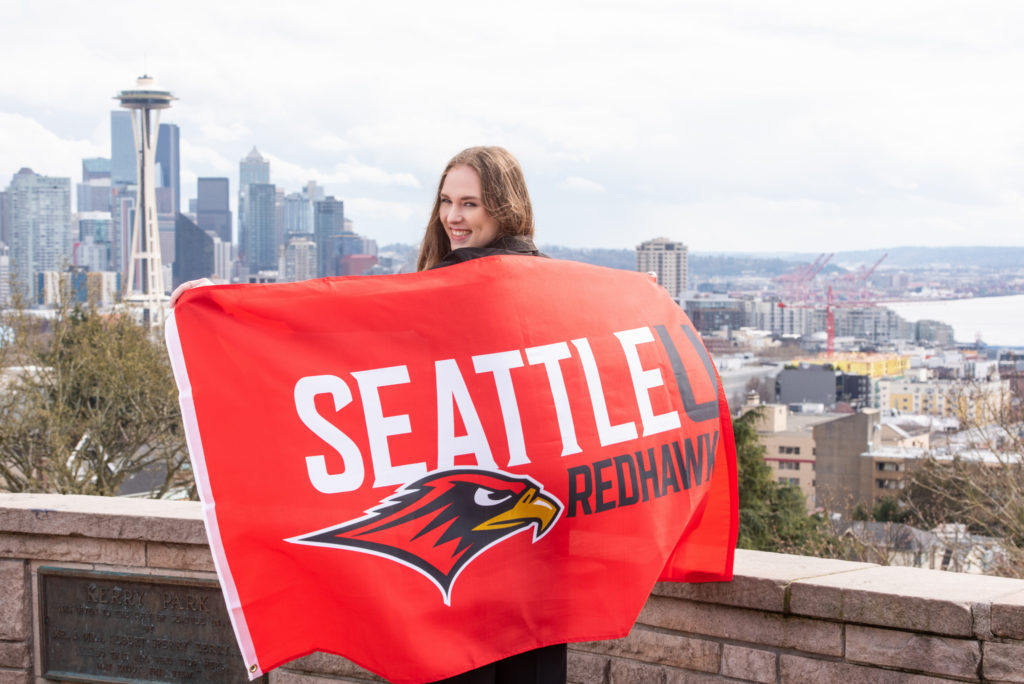 High school senior holding Seattle U flag at Kerry Park, overlooking Seattle