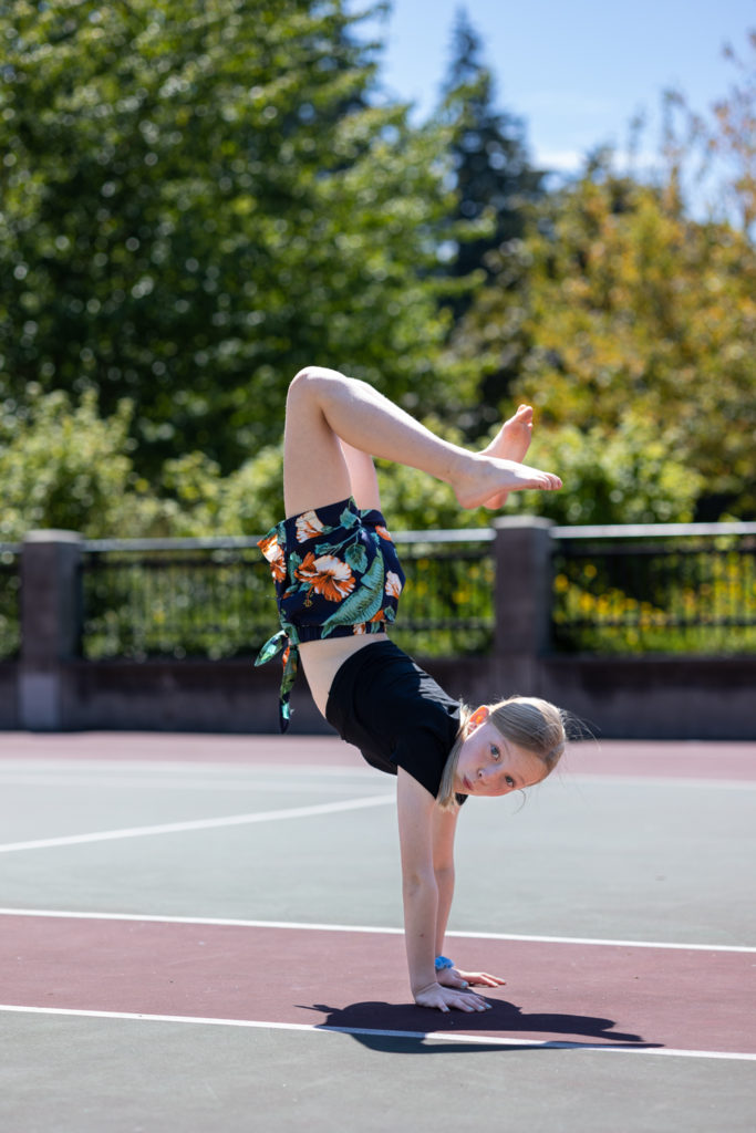 young girl doing handstand at a park