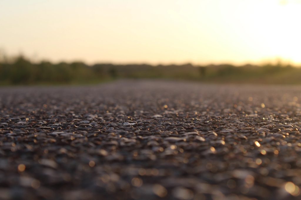 photo of pavement from a low perspective showing shallow depth of field, with a tree line off in the distance during sunset
