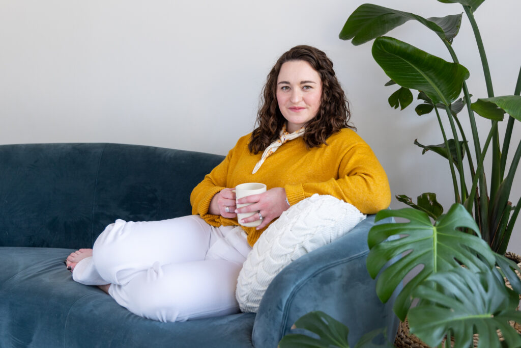 Woman sitting on a couch holding a coffee mug.