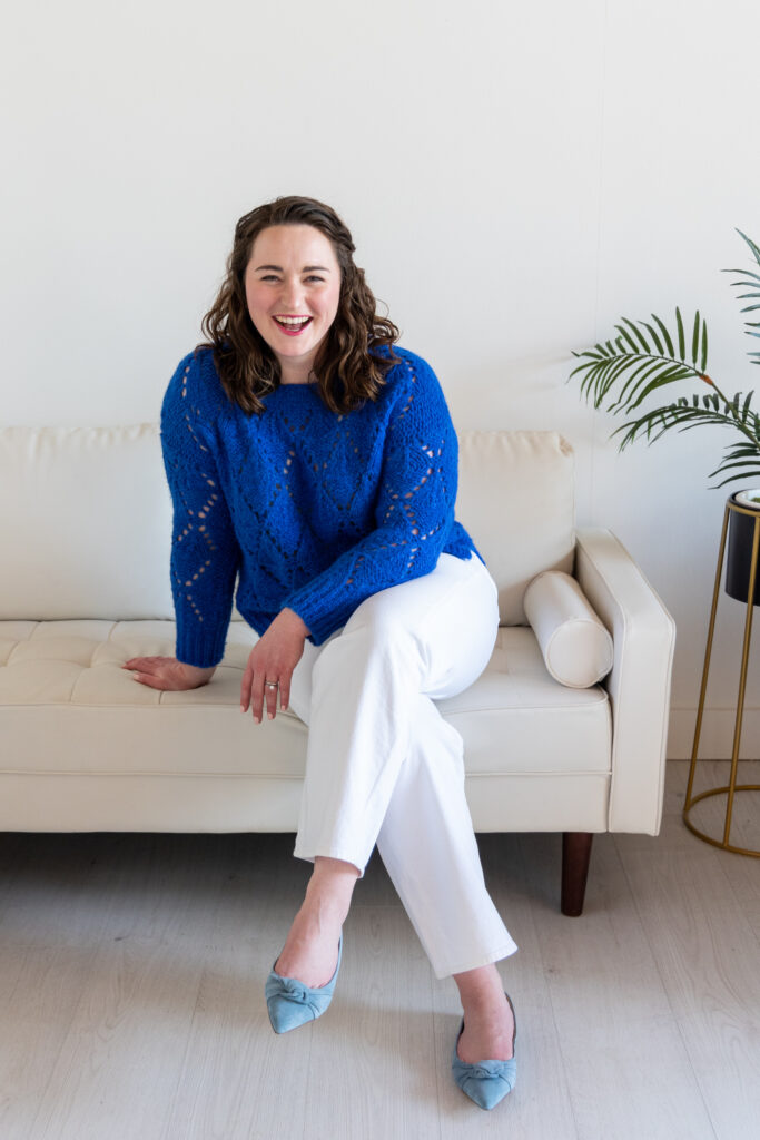 Woman sitting on a white couch, laughing.